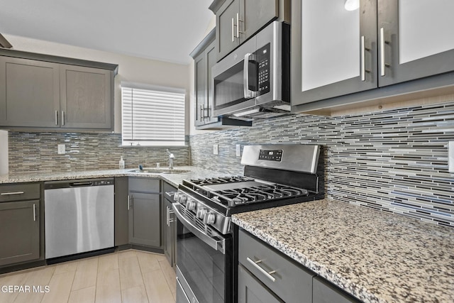 kitchen with decorative backsplash, light stone counters, sink, and stainless steel appliances