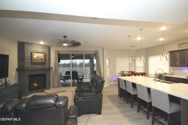 living room featuring sink, a fireplace, and ceiling fan