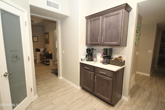 kitchen featuring light hardwood / wood-style floors, dark brown cabinets, and decorative backsplash