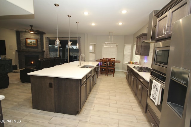 kitchen featuring sink, decorative light fixtures, ceiling fan, a kitchen island with sink, and appliances with stainless steel finishes