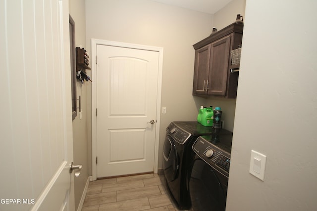 clothes washing area featuring washing machine and dryer and cabinets