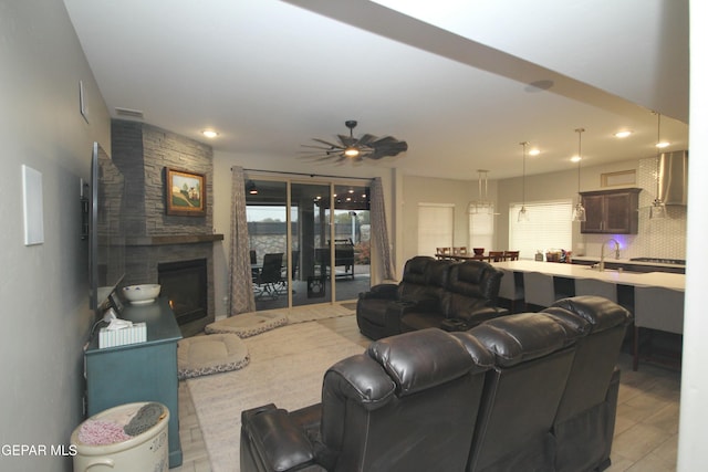 living room featuring ceiling fan and a stone fireplace