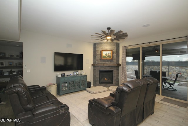 living room with ceiling fan and a stone fireplace