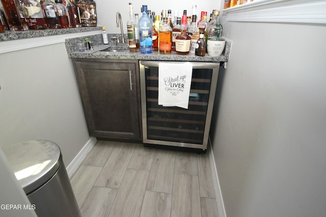 bar with sink, light hardwood / wood-style floors, and wine cooler