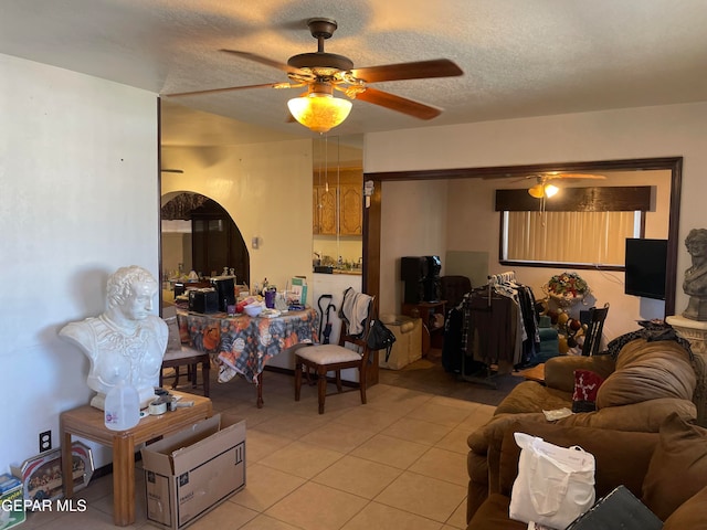 living room with ceiling fan, light tile patterned flooring, and a textured ceiling