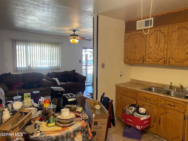 kitchen with ceiling fan, sink, light tile patterned floors, and a textured ceiling