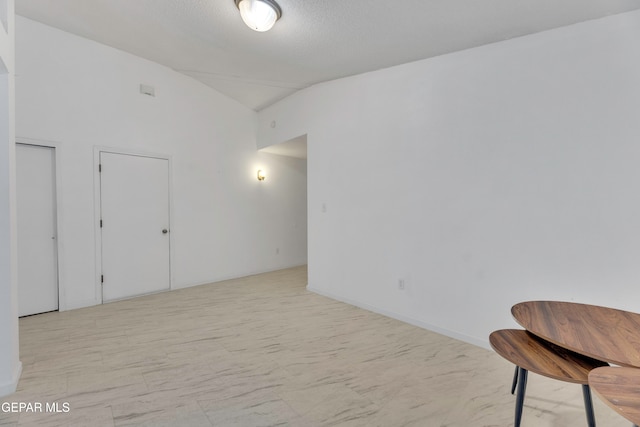 spare room with a textured ceiling and vaulted ceiling