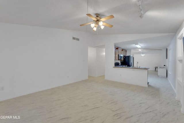 unfurnished living room with a textured ceiling, ceiling fan, rail lighting, and lofted ceiling