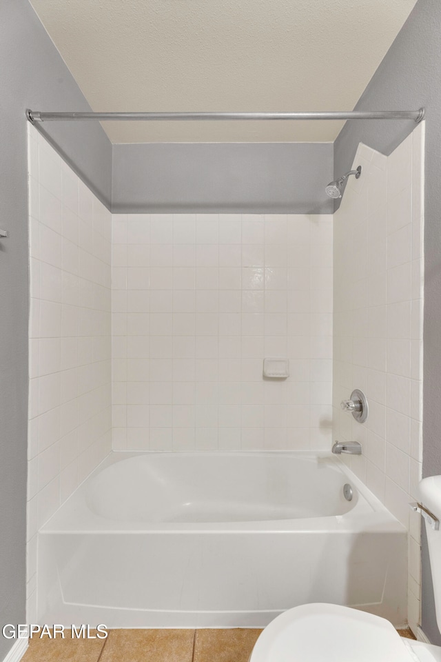 bathroom with tile patterned floors, tiled shower / bath, and toilet