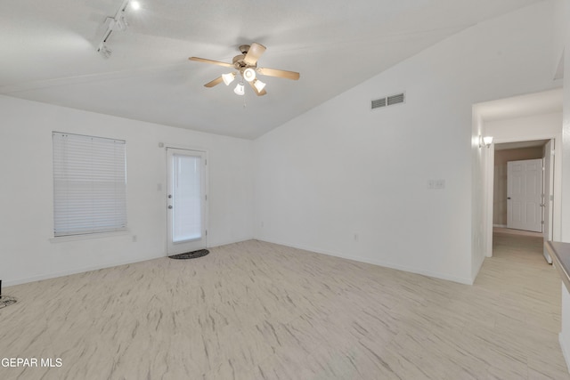 empty room featuring ceiling fan, track lighting, and vaulted ceiling