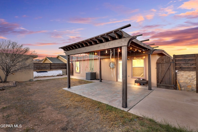 back house at dusk with central air condition unit and a patio area