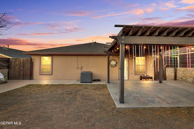 back house at dusk featuring a patio area and central AC