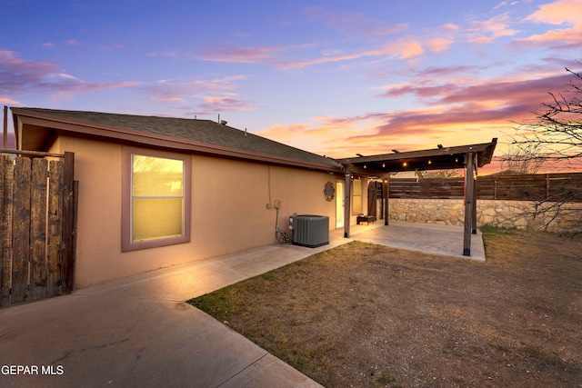 property exterior at dusk with central AC and a patio area