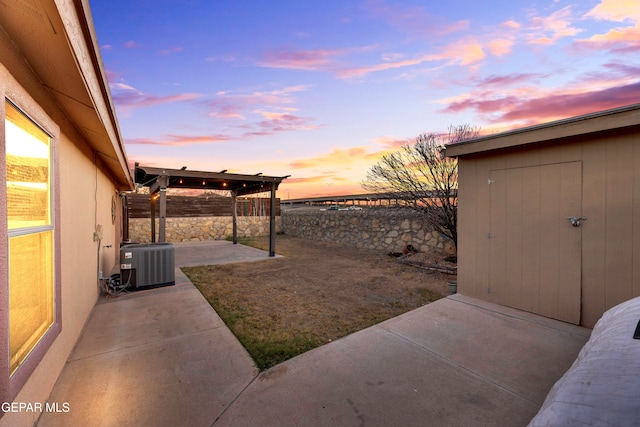 yard at dusk featuring cooling unit and a patio