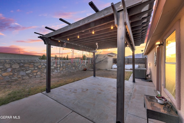 patio terrace at dusk featuring cooling unit and a storage unit