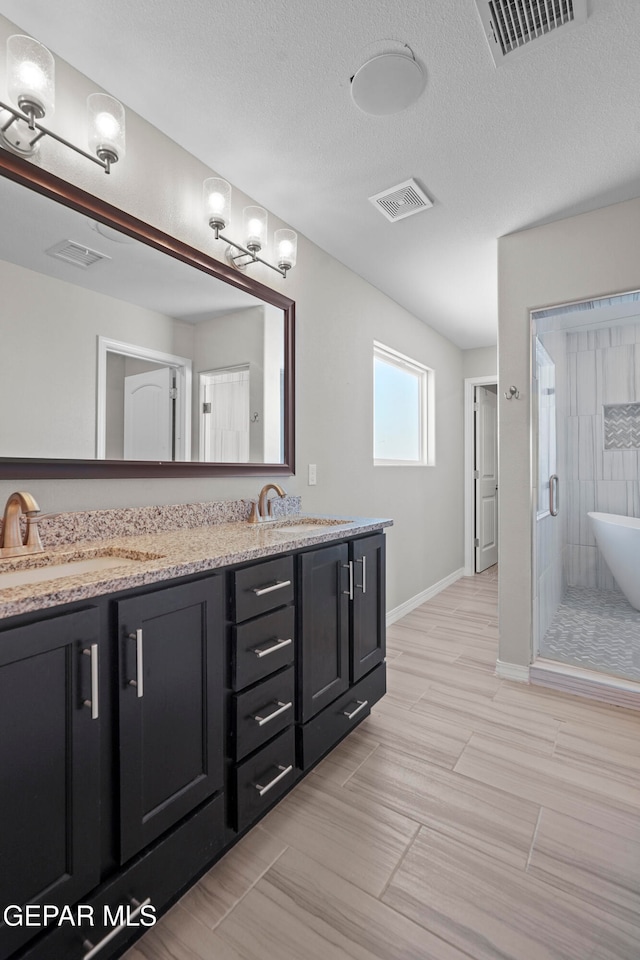 bathroom with a textured ceiling, vanity, and separate shower and tub