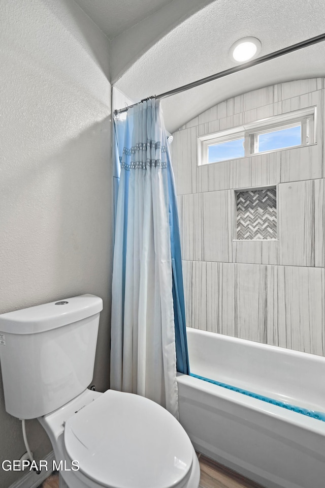 bathroom with shower / bath combo with shower curtain, hardwood / wood-style flooring, toilet, and lofted ceiling