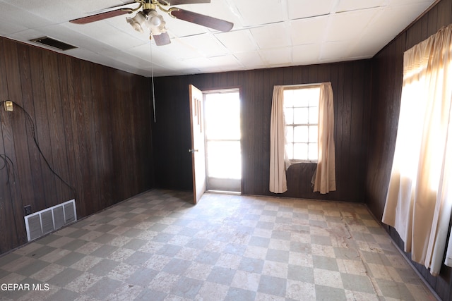 spare room featuring ceiling fan and wooden walls