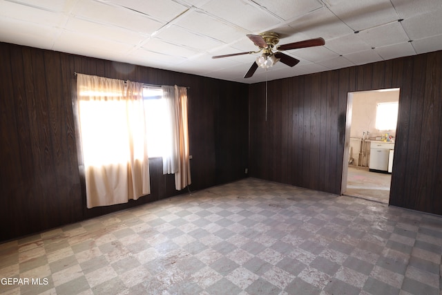 unfurnished room with ceiling fan and wooden walls