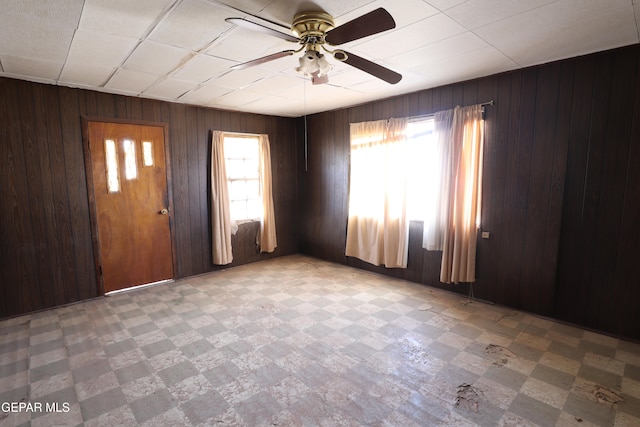 entrance foyer with ceiling fan and wood walls