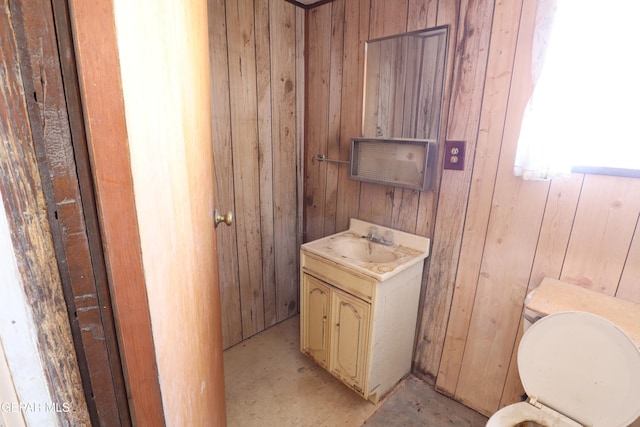 bathroom with wood walls, vanity, and toilet