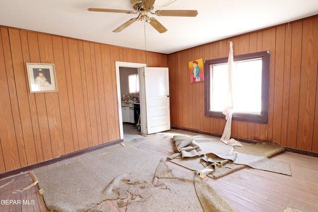 interior space featuring wooden walls, light hardwood / wood-style flooring, and ceiling fan