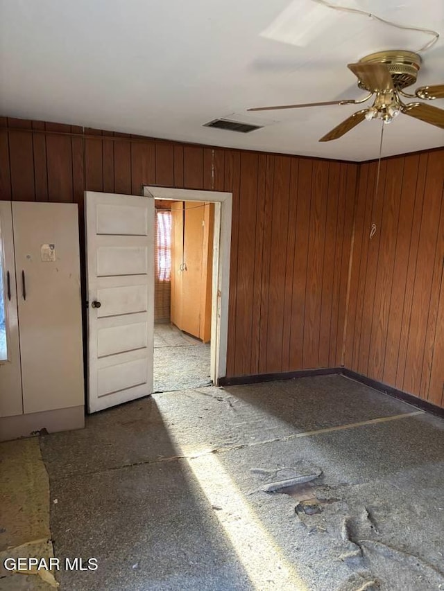 spare room with ceiling fan and wood walls