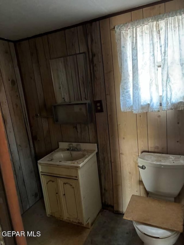 bathroom with vanity, toilet, and wooden walls