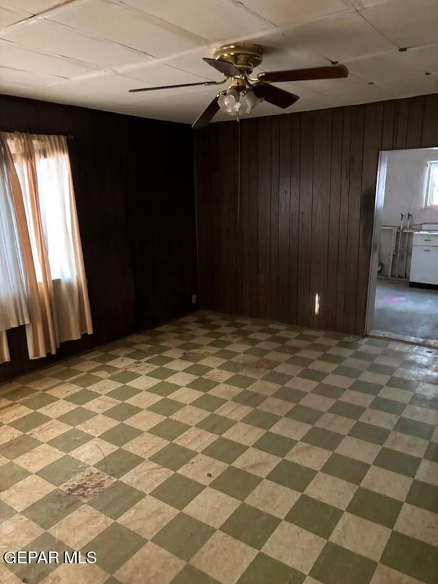 unfurnished room with wood walls and ceiling fan