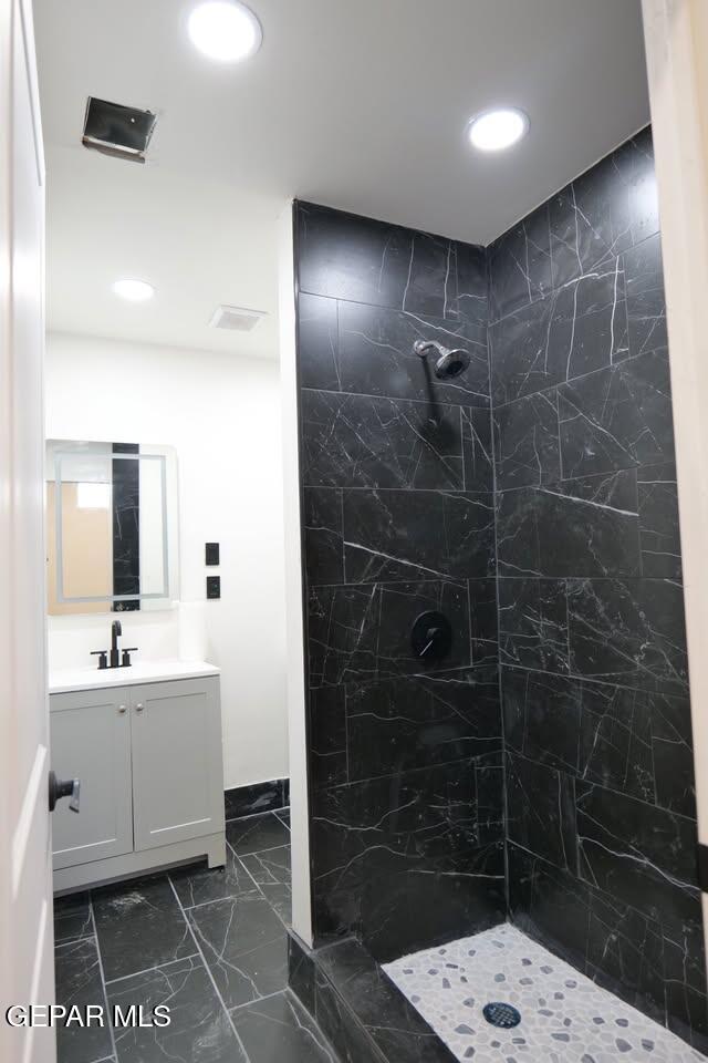 bathroom featuring a tile shower and vanity