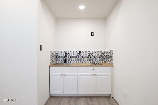 bathroom with hardwood / wood-style flooring, decorative backsplash, and sink