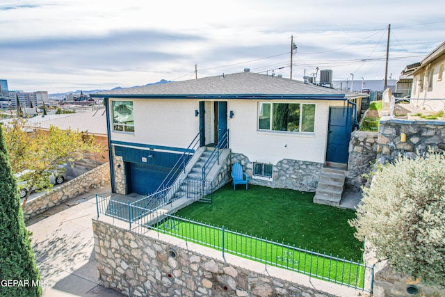 view of front facade featuring central air condition unit, a front yard, and a garage