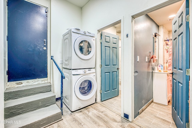 laundry area featuring stacked washer and dryer and light hardwood / wood-style flooring