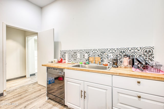 kitchen featuring sink, light hardwood / wood-style flooring, black dishwasher, butcher block countertops, and white cabinetry