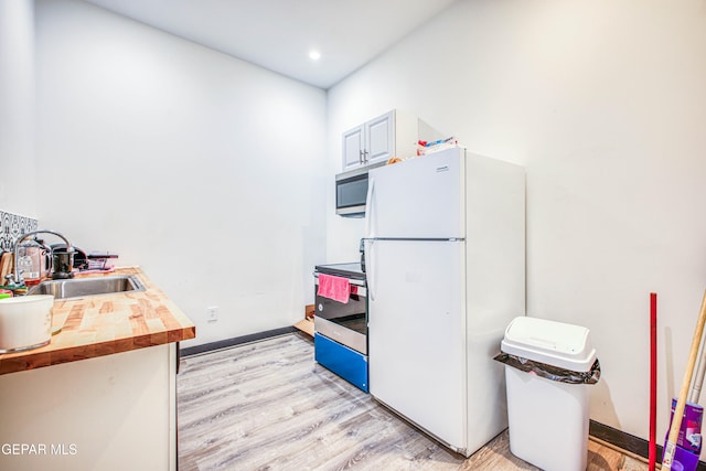 kitchen featuring appliances with stainless steel finishes, light wood-type flooring, sink, butcher block countertops, and white cabinetry