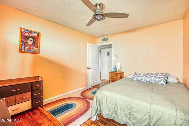 bedroom featuring wood-type flooring, a textured ceiling, and ceiling fan