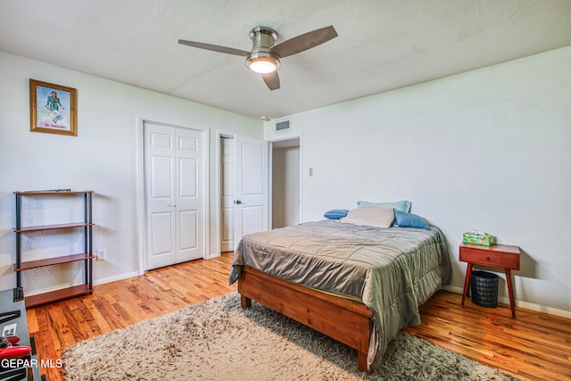 bedroom with ceiling fan, wood-type flooring, and a textured ceiling