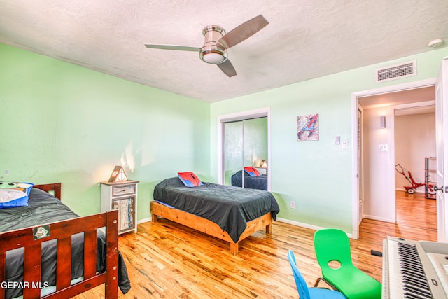 bedroom featuring ceiling fan, a closet, light hardwood / wood-style floors, and a textured ceiling