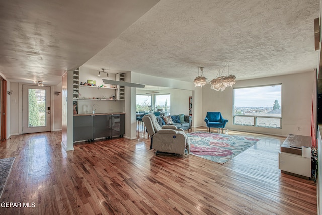 unfurnished living room featuring hardwood / wood-style flooring, sink, and a textured ceiling