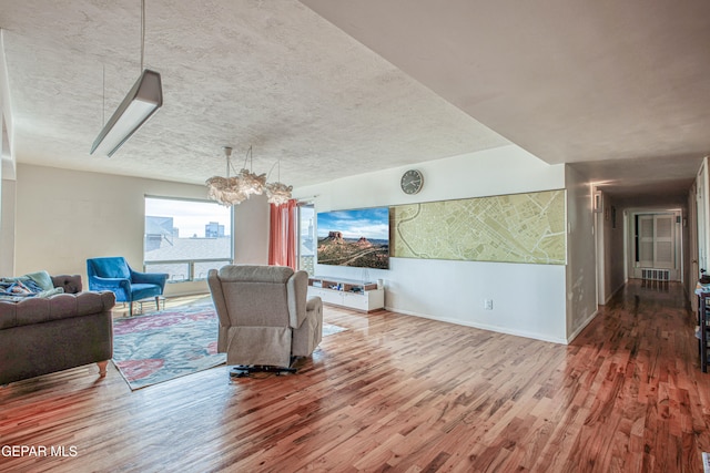 living room featuring hardwood / wood-style flooring, a textured ceiling, and an inviting chandelier