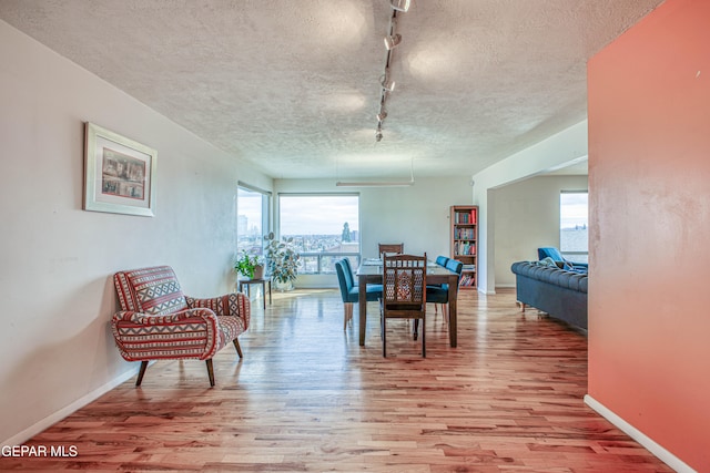 dining room with light hardwood / wood-style flooring, rail lighting, and a textured ceiling