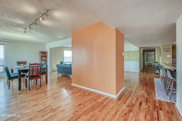 dining area featuring rail lighting, light hardwood / wood-style floors, and a textured ceiling