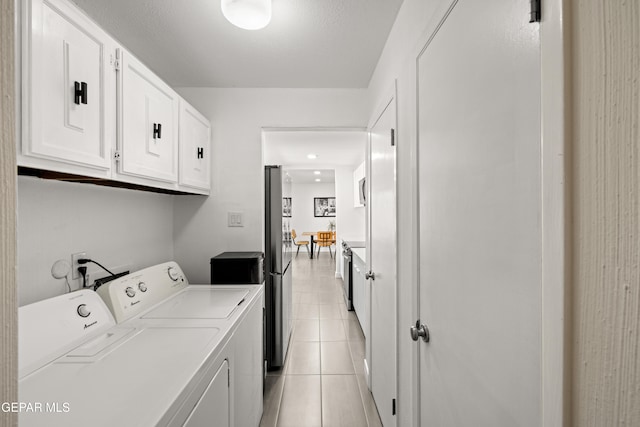 laundry room with light tile patterned flooring, cabinets, and independent washer and dryer