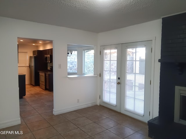 entryway with french doors, light tile patterned floors, and a textured ceiling