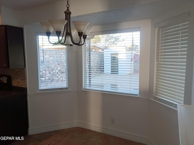 unfurnished dining area featuring tile patterned flooring and a notable chandelier