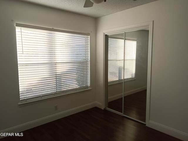 unfurnished bedroom with a textured ceiling, dark hardwood / wood-style floors, a closet, and ceiling fan