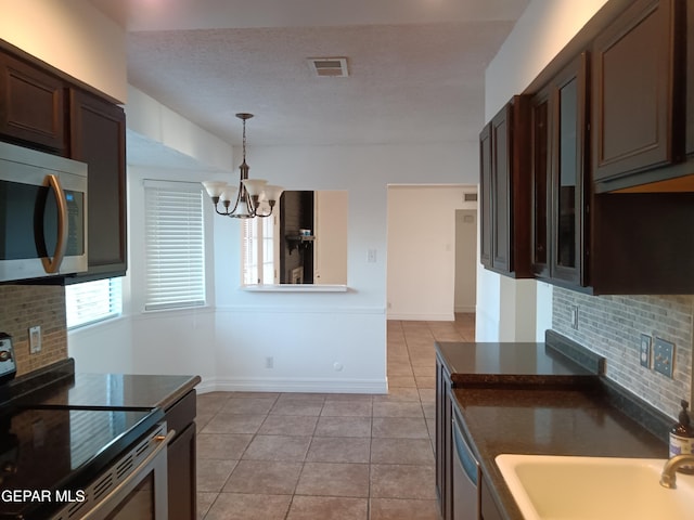 kitchen featuring appliances with stainless steel finishes, dark brown cabinetry, tasteful backsplash, and an inviting chandelier