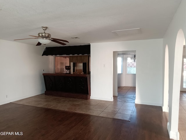 unfurnished living room with hardwood / wood-style floors, ceiling fan, and a textured ceiling