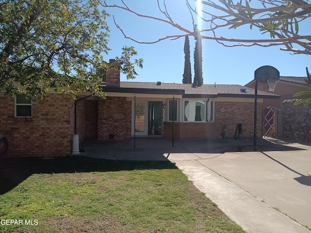 rear view of house featuring a lawn and a patio