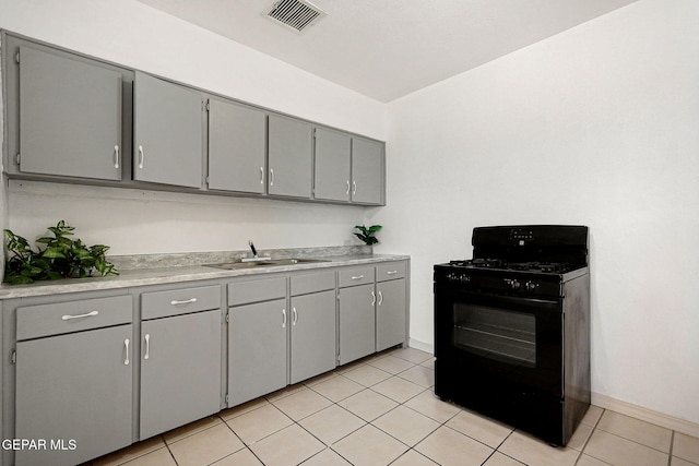 kitchen with gray cabinetry, sink, black range with gas cooktop, and light tile patterned floors